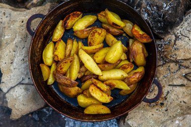 Dışarıda ateşte kızartma tavasında ev yapımı çıtır patates. Doğada piknik yapmak ve yemek yapmak..