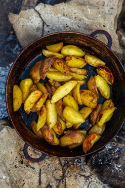 Dışarıda ateşte kızartma tavasında ev yapımı çıtır patates. Doğada piknik yapmak ve yemek yapmak..