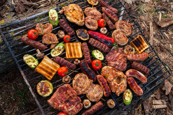 外の火の上に焼き肉の大規模な様々な 肉とピクニック ソーセージ ポークステーキ 野菜と鶏の胸肉 — ストック写真