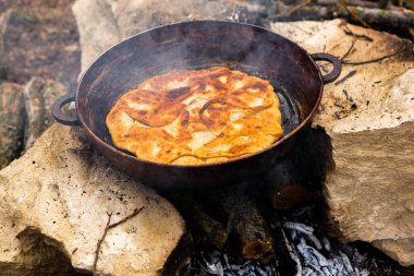 Romen geleneksel peynirli turtası dışarıdaki ateşte tavada pişiyor. Romanya ve Moldova Cumhuriyeti 'nden gıda.