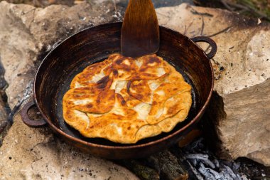 Romen geleneksel peynirli turtası dışarıdaki ateşte tavada pişiyor. Romanya ve Moldova Cumhuriyeti 'nden gıda.