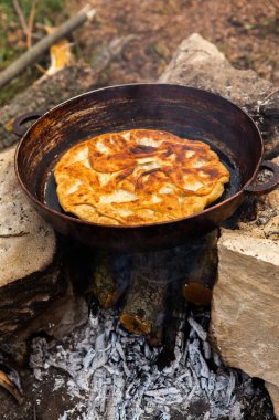 Romen geleneksel peynirli turtası dışarıdaki ateşte tavada pişiyor. Romanya ve Moldova Cumhuriyeti 'nden gıda.