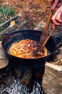 Romen geleneksel peynirli turtası dışarıdaki ateşte tavada pişiyor. Romanya ve Moldova Cumhuriyeti 'nden gıda.