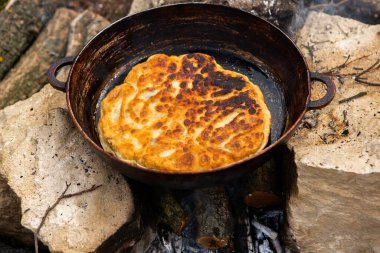 Romen geleneksel peynirli turtası dışarıdaki ateşte tavada pişiyor. Romanya ve Moldova Cumhuriyeti 'nden gıda.