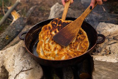 Romen geleneksel peynirli turtası dışarıdaki ateşte tavada pişiyor. Romanya ve Moldova Cumhuriyeti 'nden gıda.
