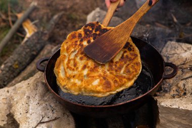 Romen geleneksel peynirli turtası dışarıdaki ateşte tavada pişiyor. Romanya ve Moldova Cumhuriyeti 'nden gıda.