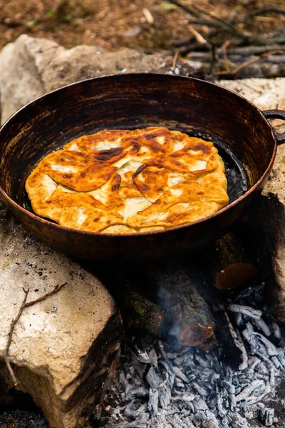 Romen geleneksel peynirli turtası dışarıdaki ateşte tavada pişiyor. Romanya ve Moldova Cumhuriyeti 'nden gıda.