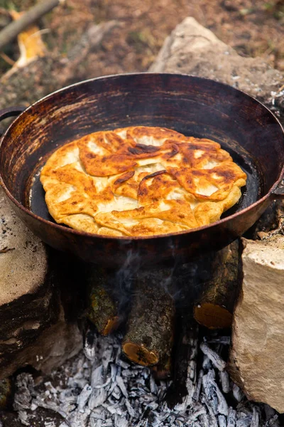 Romen geleneksel peynirli turtası dışarıdaki ateşte tavada pişiyor. Romanya ve Moldova Cumhuriyeti 'nden gıda.