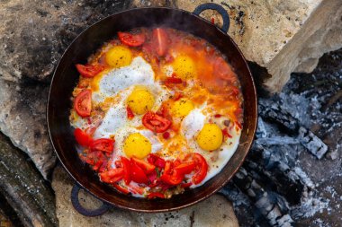 Yumurtalar, ormanda ateşte tavada sebzelerle hazırlandı. Açık ateşte çırpılmış yumurta pişirmek. Doğada kahvaltı. Turist yemeği..