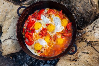 Yumurtalar, ormanda ateşte tavada sebzelerle hazırlandı. Açık ateşte çırpılmış yumurta pişirmek. Doğada kahvaltı. Turist yemeği..