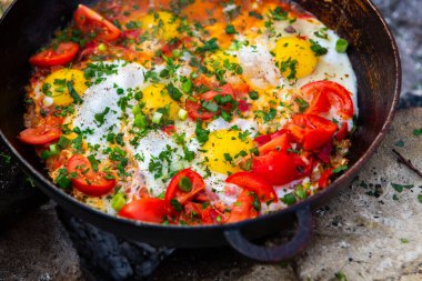 Yumurtalar, ormanda ateşte tavada sebzelerle hazırlandı. Açık ateşte çırpılmış yumurta pişirmek. Doğada kahvaltı. Turist yemeği..
