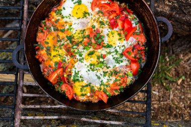 Yumurtalar, ormanda ateşte tavada sebzelerle hazırlandı. Açık ateşte çırpılmış yumurta pişirmek. Doğada kahvaltı. Turist yemeği..