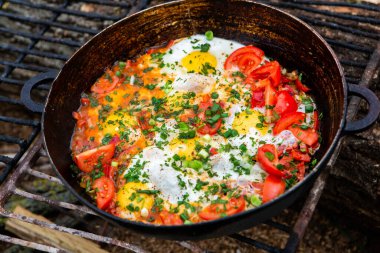 Yumurtalar, ormanda ateşte tavada sebzelerle hazırlandı. Açık ateşte çırpılmış yumurta pişirmek. Doğada kahvaltı. Turist yemeği..