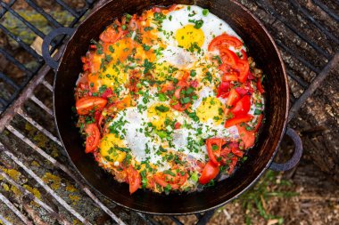 Yumurtalar, ormanda ateşte tavada sebzelerle hazırlandı. Açık ateşte çırpılmış yumurta pişirmek. Doğada kahvaltı. Turist yemeği..