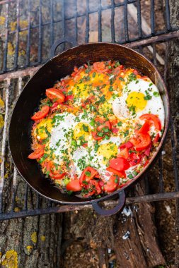 Yumurtalar, ormanda ateşte tavada sebzelerle hazırlandı. Açık ateşte çırpılmış yumurta pişirmek. Doğada kahvaltı. Turist yemeği..