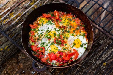 Yumurtalar, ormanda ateşte tavada sebzelerle hazırlandı. Açık ateşte çırpılmış yumurta pişirmek. Doğada kahvaltı. Turist yemeği..