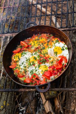 Yumurtalar, ormanda ateşte tavada sebzelerle hazırlandı. Açık ateşte çırpılmış yumurta pişirmek. Doğada kahvaltı. Turist yemeği..