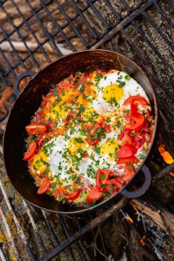Yumurtalar, ormanda ateşte tavada sebzelerle hazırlandı. Açık ateşte çırpılmış yumurta pişirmek. Doğada kahvaltı. Turist yemeği..