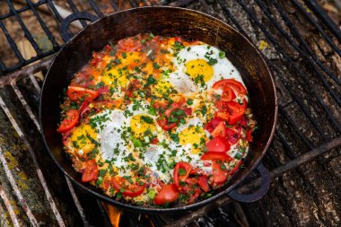 Yumurtalar, ormanda ateşte tavada sebzelerle hazırlandı. Açık ateşte çırpılmış yumurta pişirmek. Doğada kahvaltı. Turist yemeği..