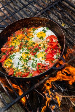 Yumurtalar, ormanda ateşte tavada sebzelerle hazırlandı. Açık ateşte çırpılmış yumurta pişirmek. Doğada kahvaltı. Turist yemeği..