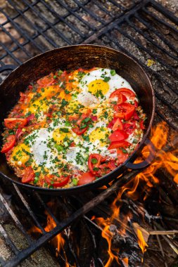 Yumurtalar, ormanda ateşte tavada sebzelerle hazırlandı. Açık ateşte çırpılmış yumurta pişirmek. Doğada kahvaltı. Turist yemeği..