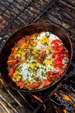 Yumurtalar, ormanda ateşte tavada sebzelerle hazırlandı. Açık ateşte çırpılmış yumurta pişirmek. Doğada kahvaltı. Turist yemeği..