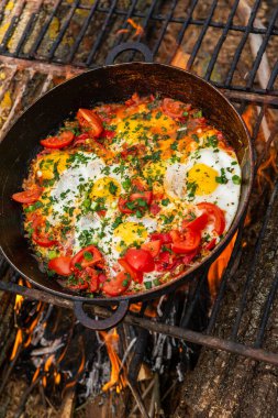 Yumurtalar, ormanda ateşte tavada sebzelerle hazırlandı. Açık ateşte çırpılmış yumurta pişirmek. Doğada kahvaltı. Turist yemeği..