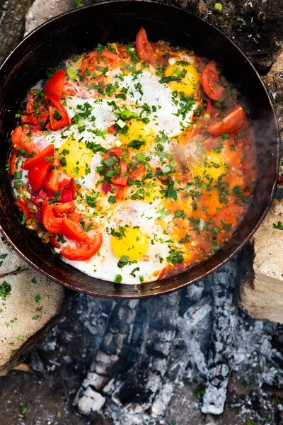 Yumurtalar, ormanda ateşte tavada sebzelerle hazırlandı. Açık ateşte çırpılmış yumurta pişirmek. Doğada kahvaltı. Turist yemeği..