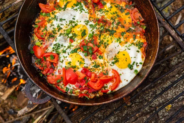 Yumurtalar, ormanda ateşte tavada sebzelerle hazırlandı. Açık ateşte çırpılmış yumurta pişirmek. Doğada kahvaltı. Turist yemeği..
