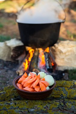 Açık ateşte hazırlanmış balık çorbası. Çaydanlıkta açık ateşte balık çorbası pişirmek. Turizm ve balıkçılıkta yemek pişirmek