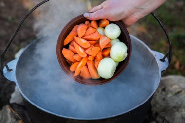 Açık ateşte hazırlanmış balık çorbası. Çaydanlıkta açık ateşte balık çorbası pişirmek. Turizm ve balıkçılıkta yemek pişirmek