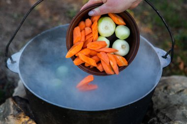 Açık ateşte hazırlanmış balık çorbası. Çaydanlıkta açık ateşte balık çorbası pişirmek. Turizm ve balıkçılıkta yemek pişirmek