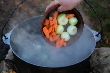 Açık ateşte hazırlanmış balık çorbası. Çaydanlıkta açık ateşte balık çorbası pişirmek. Turizm ve balıkçılıkta yemek pişirmek