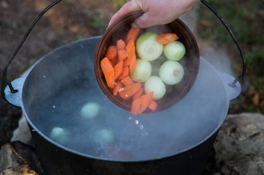 Açık ateşte hazırlanmış balık çorbası. Çaydanlıkta açık ateşte balık çorbası pişirmek. Turizm ve balıkçılıkta yemek pişirmek