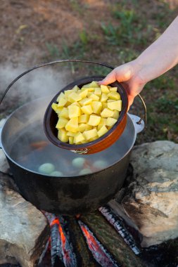 Açık ateşte hazırlanmış balık çorbası. Çaydanlıkta açık ateşte balık çorbası pişirmek. Turizm ve balıkçılıkta yemek pişirmek