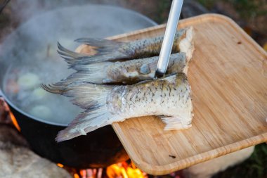Açık ateşte hazırlanmış balık çorbası. Çaydanlıkta açık ateşte balık çorbası pişirmek. Turizm ve balıkçılıkta yemek pişirmek