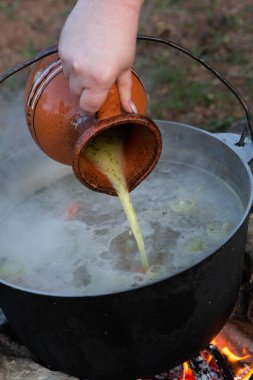 Açık ateşte hazırlanmış balık çorbası. Çaydanlıkta açık ateşte balık çorbası pişirmek. Turizm ve balıkçılıkta yemek pişirmek