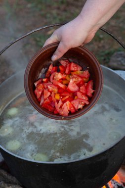 Açık ateşte hazırlanmış balık çorbası. Çaydanlıkta açık ateşte balık çorbası pişirmek. Turizm ve balıkçılıkta yemek pişirmek