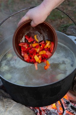 Açık ateşte hazırlanmış balık çorbası. Çaydanlıkta açık ateşte balık çorbası pişirmek. Turizm ve balıkçılıkta yemek pişirmek