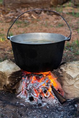 Açık ateşte hazırlanmış balık çorbası. Çaydanlıkta açık ateşte balık çorbası pişirmek. Turizm ve balıkçılıkta yemek pişirmek