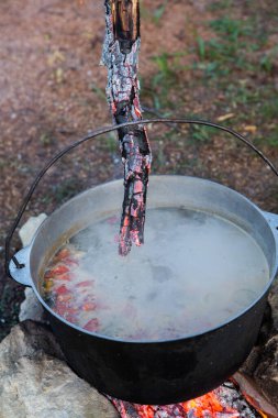 Açık ateşte hazırlanmış balık çorbası. Çaydanlıkta açık ateşte balık çorbası pişirmek. Turizm ve balıkçılıkta yemek pişirmek