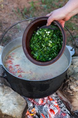 Açık ateşte hazırlanmış balık çorbası. Çaydanlıkta açık ateşte balık çorbası pişirmek. Turizm ve balıkçılıkta yemek pişirmek