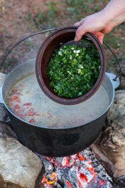 Fish soup prepared over an open fire. Cooking fish soup over an open fire in a kettle. Cooking in hiking tourism and fishing clipart