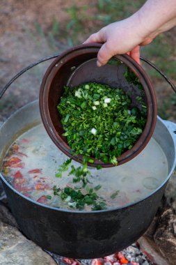 Açık ateşte hazırlanmış balık çorbası. Çaydanlıkta açık ateşte balık çorbası pişirmek. Turizm ve balıkçılıkta yemek pişirmek