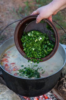 Açık ateşte hazırlanmış balık çorbası. Çaydanlıkta açık ateşte balık çorbası pişirmek. Turizm ve balıkçılıkta yemek pişirmek