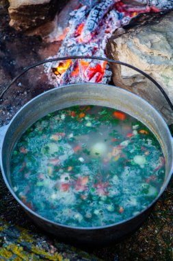 Açık ateşte hazırlanmış balık çorbası. Çaydanlıkta açık ateşte balık çorbası pişirmek. Turizm ve balıkçılıkta yemek pişirmek