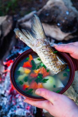 Açık ateşte hazırlanmış balık çorbası. Çaydanlıkta açık ateşte balık çorbası pişirmek. Turizm ve balıkçılıkta yemek pişirmek