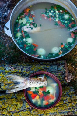 Açık ateşte hazırlanmış balık çorbası. Çaydanlıkta açık ateşte balık çorbası pişirmek. Turizm ve balıkçılıkta yemek pişirmek
