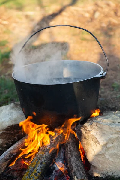 Açık ateşte hazırlanmış balık çorbası. Çaydanlıkta açık ateşte balık çorbası pişirmek. Turizm ve balıkçılıkta yemek pişirmek