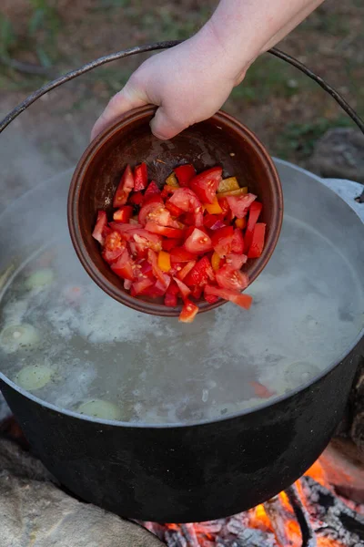 Açık ateşte hazırlanmış balık çorbası. Çaydanlıkta açık ateşte balık çorbası pişirmek. Turizm ve balıkçılıkta yemek pişirmek